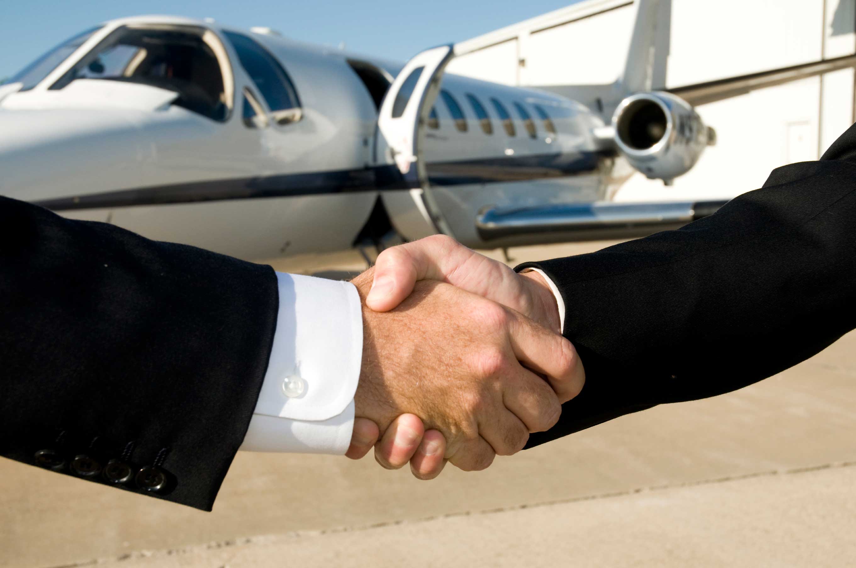 two shaking hands corporate business jet